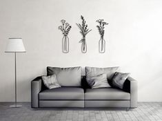 two vases with flowers are on the wall next to a couch in a living room