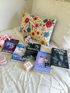 a bed topped with lots of books on top of it next to pillows and flowers