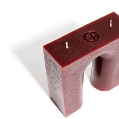 a candle that is sitting on top of a block of red soap with water droplets all over it