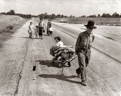 a group of people walking down a dirt road next to a baby in a stroller