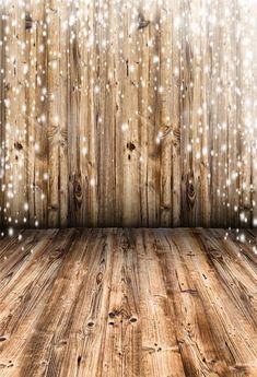 an empty wooden room with snow falling down the wall and wood flooring in front of it