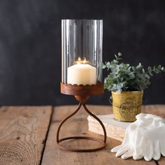 a candle is sitting on top of a wooden table next to a potted plant