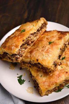 three pieces of meat and cheese pastries on a white plate