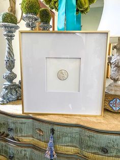 a vase with flowers in it sitting next to a picture frame on a dresser top