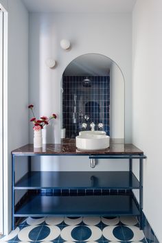 a bathroom with a sink, mirror and blue tile on the floor in front of it