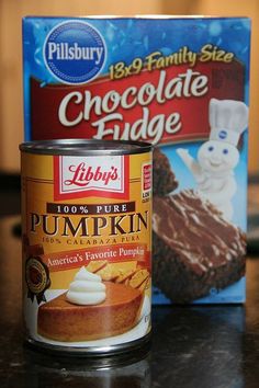 a can of chocolate fudge next to a box of pumpkin cake mix on a table