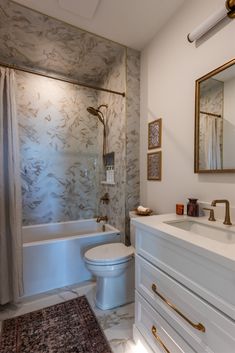 a bathroom with a sink, toilet and bathtub next to a rug on the floor