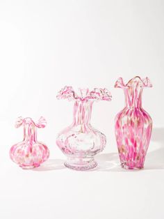 three glass vases with pink and white designs on them