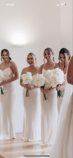 a group of women standing next to each other in front of a mirror holding bouquets