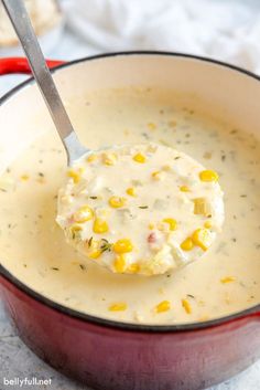 a spoon full of soup with corn in it