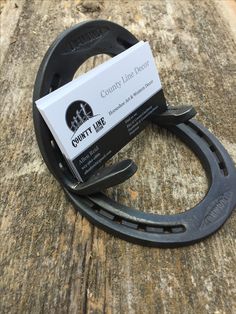 a pair of black scissors sitting on top of a wooden table next to a business card