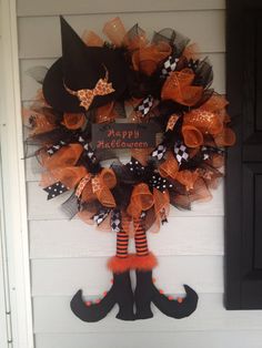 an orange and black wreath with witch hats on it's front door for halloween