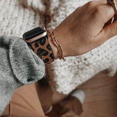 a woman wearing an apple watch on her wrist with a leopard print bracelet around her arm