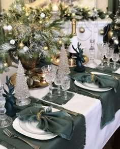 the table is set for christmas dinner with green and gold decorations