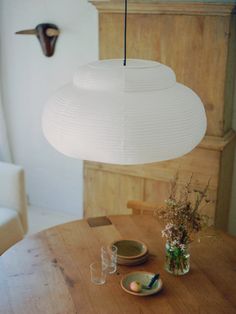 a wooden table with plates and vases sitting on it next to a light fixture