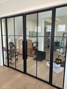 a person is sitting on the floor in front of some glass doors that are open