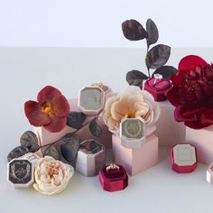 there are many different types of flowers in the vases and boxes on the table