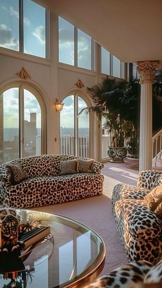 a living room filled with lots of furniture next to tall windows on top of a building