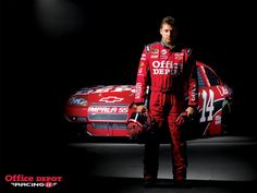 a man standing next to a racing car in front of a black background with the words stewart has racing written on it