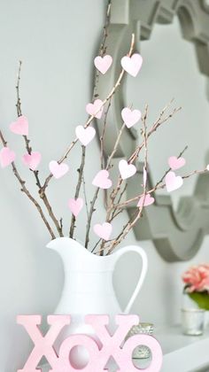 a white vase filled with pink hearts sitting on top of a table next to a mirror