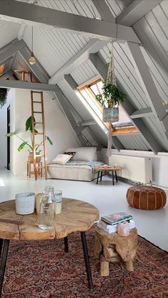 a living room filled with furniture and a wooden table in front of a loft window