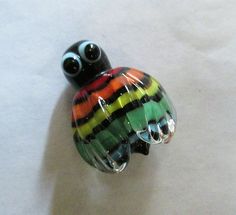 a colorful glass turtle sitting on top of a white table next to a black and red object