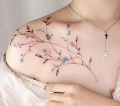 a woman's chest with blue flowers and a cross on it