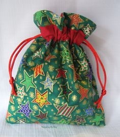 a small green bag with red string and stars on it, sitting on a white surface