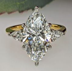 a close up of a ring with a large diamond on the center and two smaller diamonds at the bottom