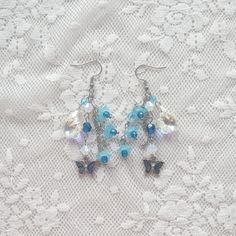 two pairs of blue and white beaded earrings sitting on top of a lace covered surface