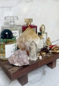 a wooden table topped with lots of different types of perfumes and rocks on top of it