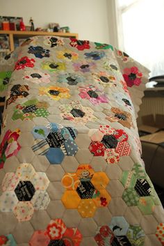 a bed covered in a colorful quilt next to a window