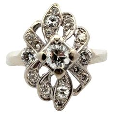 This stunning 1950's vintage cocktail ring handcrafted in 14 karat white gold is an example of timeless elegance and glamour. The ring is adorned with an approximate .38 carat Old European cut center diamond and 16 accent diamonds weighing another .70 CTW. The diamonds are graded G-H color and SI clarity. The ring features an elonated design measuring 14 x 20mm, and is currently size 6.75 (can be sized). Weight: 4.0 grams. Art Deco Diamond Cluster Ring With 17 Jewels, Fine Jewelry Platinum Diamond Ring For Evening, Evening Platinum Diamond Ring Fine Jewelry, Evening Platinum Diamond Ring, Fine Jewelry Style, White Diamond Art Deco Cluster Ring, Platinum Diamond White Ring For Evening, Platinum Diamond Ring For Evening, Evening Platinum Diamond Ring, Art Deco Diamond White Diamond Ring With Prong Setting