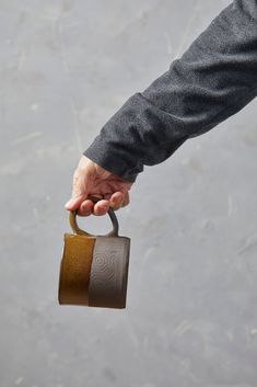 a person holding a coffee cup in their hand with the handle extended to grab it