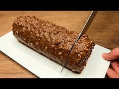 a person is cutting into a cake with chocolate frosting and nuts on the top