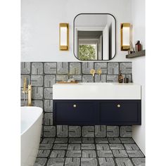 a bathroom with black and white tiles on the floor, gold trim around the mirror