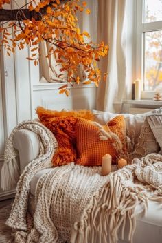 a white couch with pillows and blankets on top of it in front of a window