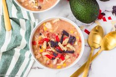 two bowls of soup with tortilla chips and avocado on the side