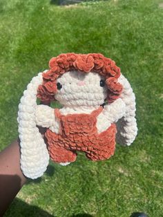 a crocheted stuffed animal is being held by someone's hand in the grass