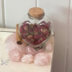 a glass jar filled with lots of pink flowers next to some rocks and a cinnamon stick