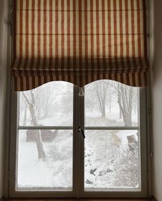 the window is covered in snow and has an orange striped roman blind on it's side