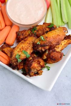 chicken wings with carrots, celery and celery sticks on a white plate