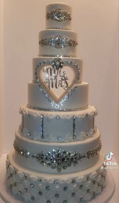 a three tiered wedding cake with hearts on the top and initials on the bottom