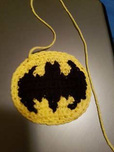 a crocheted bag with a bat motif on it sitting on a table next to a blue object