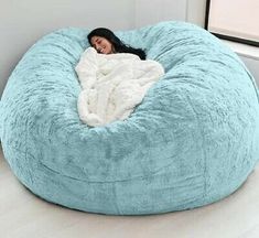 a woman laying in a large blue bean bag chair