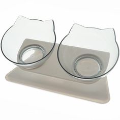 two glass bowls sitting on top of a white tray with one bowl in the shape of a cat's head