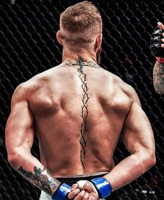 a man with tattoos on his back holding a blue boxing glove