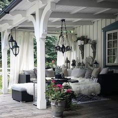 an outdoor living area with white walls and wood floors, covered in curtains and furniture