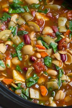 a close up of a stew in a crock pot with carrots, beans and spinach