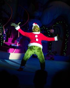 a man dressed as the grinch in front of an audience at a christmas show